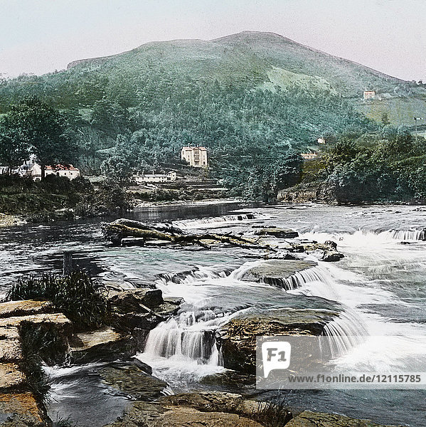 Magic Lantern slide circa 1900 hand coloured. created in 1887. A tour of North Wales. Llangollen—the River and Barber’s Hill.—This scene  whilst displaying the river to more ad¬vantage  is a fair specimen of the beauty of Llangollen’s neighbourhood. For quiet rest and gentle exercise  few similar natural pleasure resorts are to be found in Wales. Llangollen is celebrated as once being the home of two ladies who declared their independence and desire to avoid matrimonial engagement by living alone  in a little cottage still to be seen on the South side of the vale. The fact is recorded in the Welsh song :— “ In the Vale of Llangollen a cottage ia seen  Well shelter’d from tempests by shades ever green  There the daisy first opens its eye to the day  And the hawthorn first blooms on the bosom of May. There  far from the haunts of ambition and pride. Contentment and virtue and friendship abide  And Nature complacent smiles sweet on the pair  Who have spendour forsaken  to worship her there.