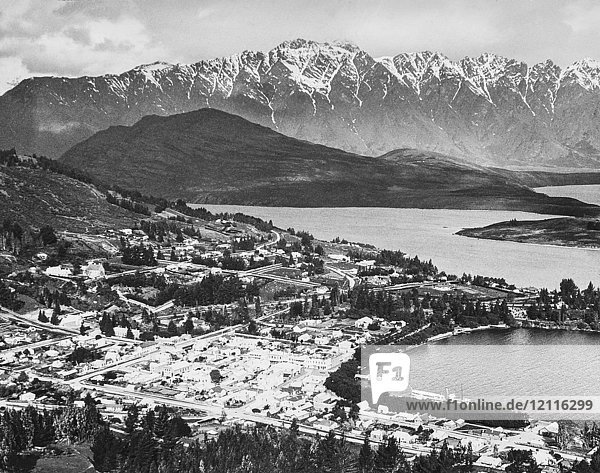 Magic lantern slide circa 1900.Victorian/Edwardian social history. A view from the hills to Queenstown and the Remarkables. New Zealand harbour with ships and paddle steamers