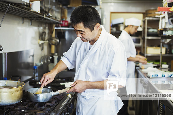 Chef working in the kitchen of a Japanese sushi restaurant  cooking on stove.