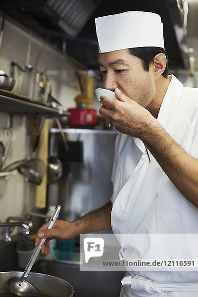 Chefkoch  der in der Küche eines japanischen Sushi-Restaurants arbeitet und Essen verkostet.