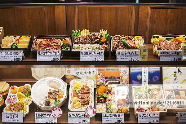 Hochwinkelansicht einer Auswahl von Bento-Schachteln mit traditionellen japanischen Lebensmitteln in den Regalen.