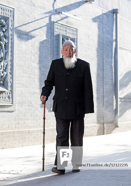 Hui muslim man walking with cane in the street  Gansu province  Linxia  China.
