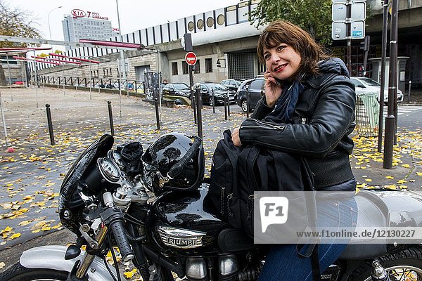 Paris  France. Adult woman sitting on her Triumph Motor Bike just after an accident  waiting for a tow truck to haul er to the garage. Well educated and professional working women choose their own  alternative means of transport during commutes.