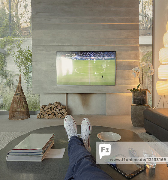 Persönliche Perspektive Frau schaut Fußball im Fernsehen im Wohnzimmer