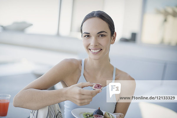 Porträt einer lächelnden  selbstbewussten brünetten Frau  die Feigen isst