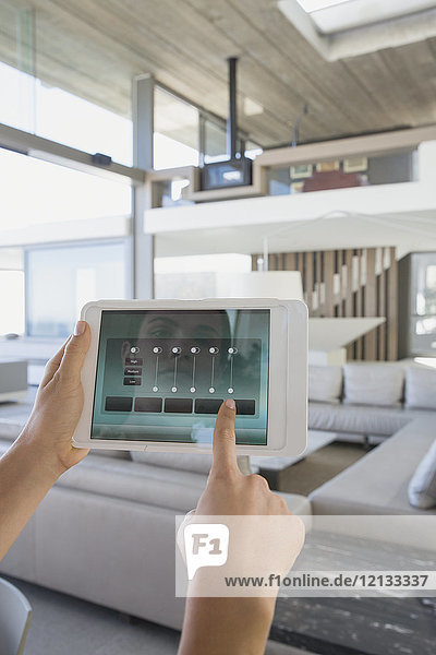 Persönliche Perspektive Frau mit digitaler Tablette Einstellung digitaler Klimasteuerung in modernen  luxuriösen Hause Showcase Innenraum Wohnzimmer