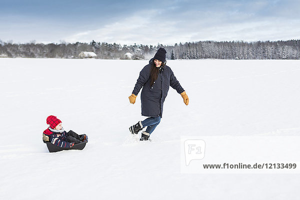 Mutter spielt mit Kind im Schnee in Schweden