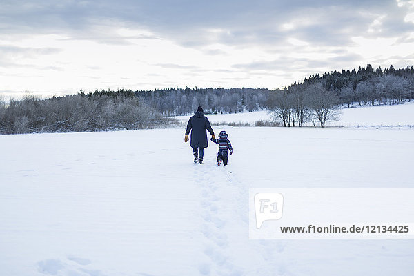 Rückansicht von Mutter und Kind beim Wandern im Schnee