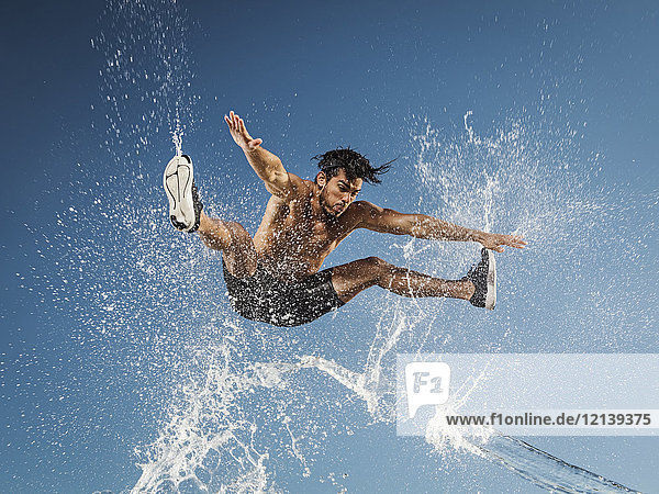 Wasser spritzt auf springenden hispanischen Mann