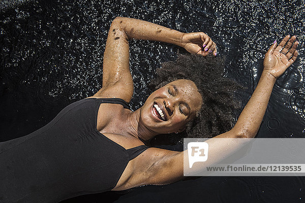 Laughing black woman laying in water