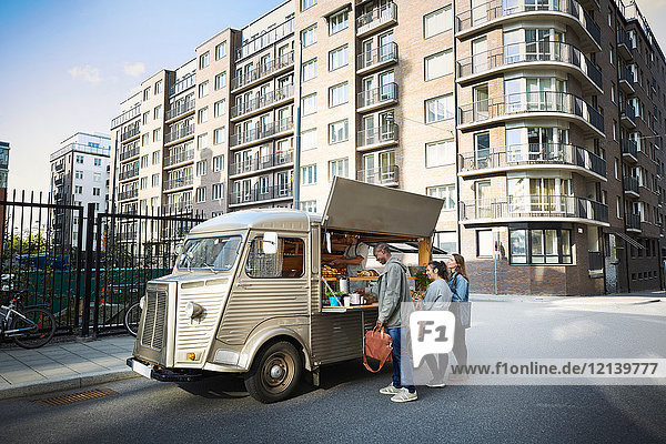 Männliche und weibliche Kunden die am Food-Truck in der Stadt bestellen.