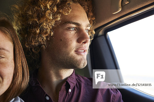 Junges Paar im Auto  junger Mann schaut durchs Fenster