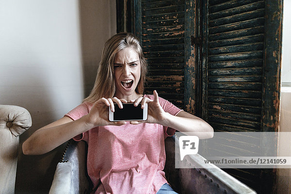 Schreiende junge Frau nimmt Smartphone Selfie