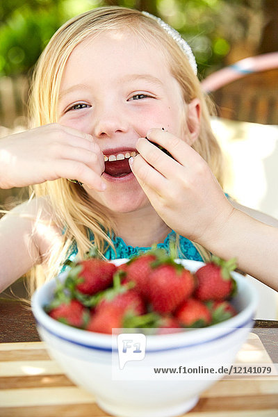 Porträt eines glücklichen Mädchens  das Erdbeeren isst.
