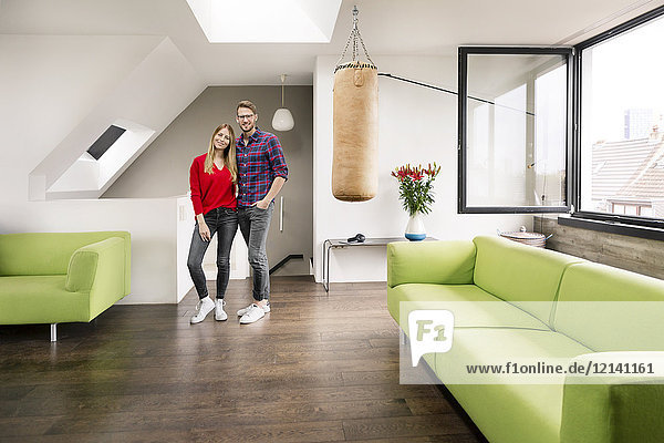 Portrait of smiling young couple standing in living room at home