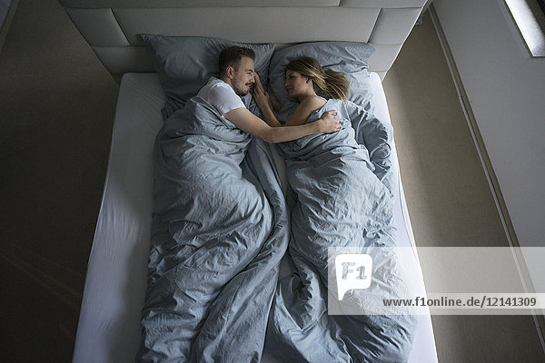 Top view of affectionate couple lying in bed at home