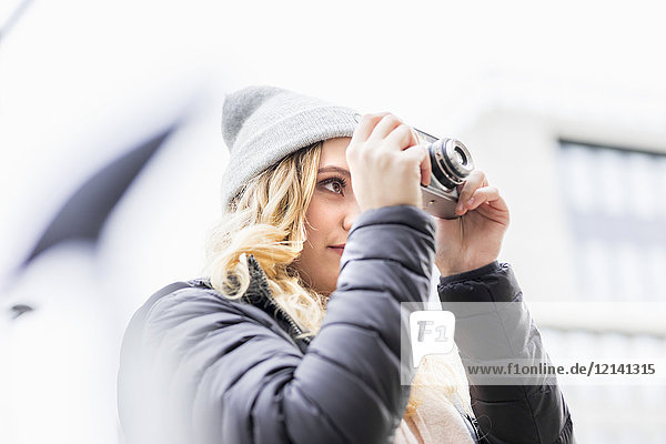 Junge Frau beim Fotografieren mit Vintage-Kamera