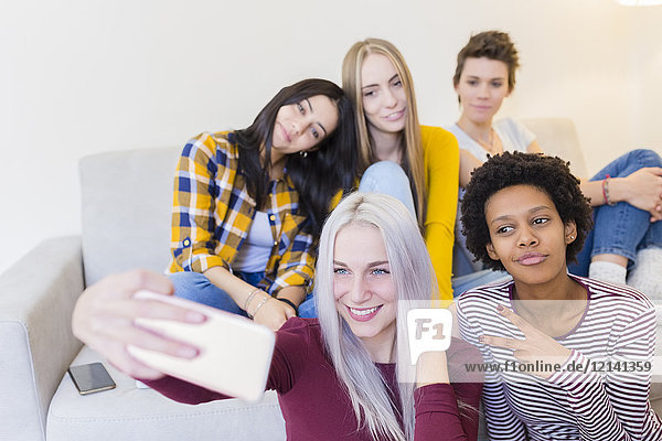 Glückliche weibliche Freunde  die einen Selfie im Wohnzimmer nehmen.