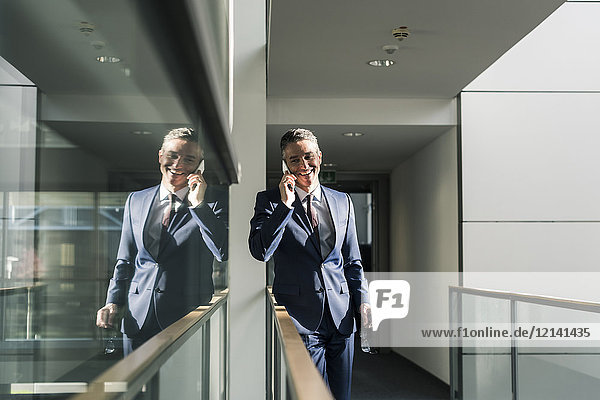 Smiling businessman talking on cell phone on office floor