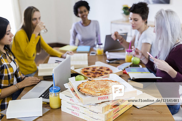 Group of young women at home studying and having pizza