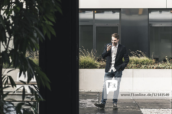 Junger Geschäftsmann mit Smartphone außerhalb des Büros