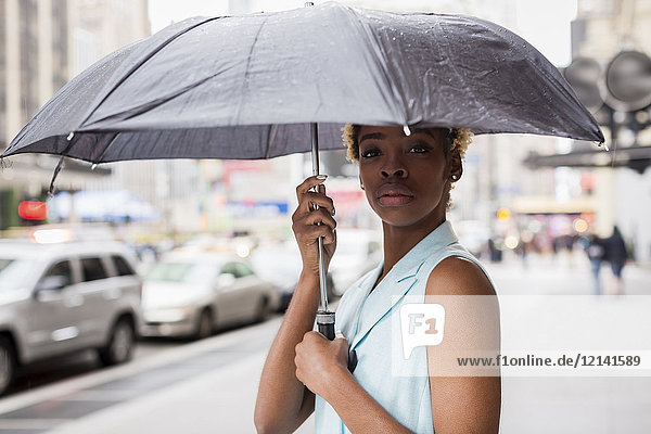USA  New York  Portrait einer jungen blonden Afroamerikanerin mit Regenschirm