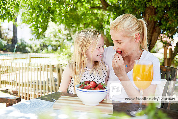 Mädchen mit Mutter beim Essen von Erdbeeren