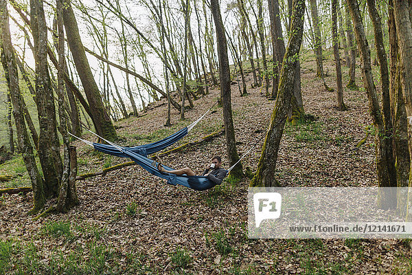 Germany  Rhineland-Palatinate  Vulkan Eifel  young man lying in hammock in forest