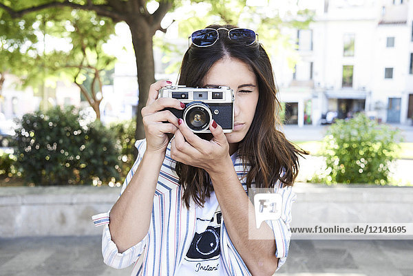 Junge Frau beim Fotografieren mit Vintage-Kamera