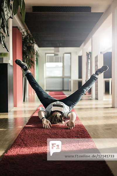 Geschäftsmann auf Teppichboden liegend mit VR-Brille beim Training
