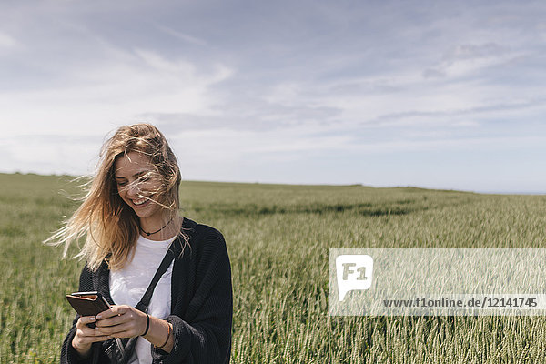 Junge Frau mit Smartphone  im Feld stehend