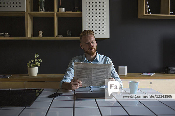 Businessman reading newspaper at home