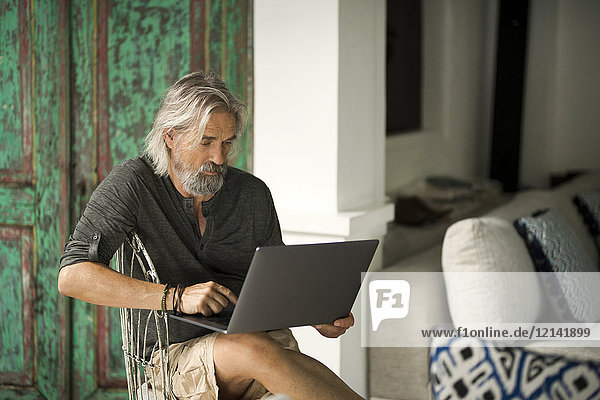 Älterer Mann bei der Arbeit am Laptop in seinem stilvollen Zuhause