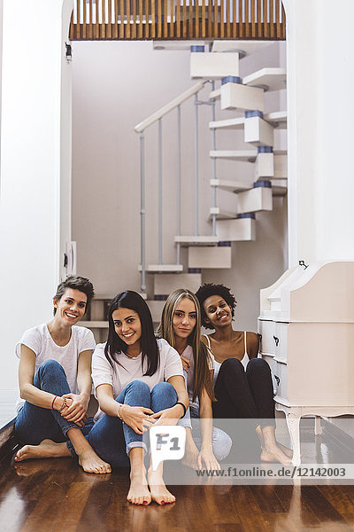Portrait of smiling female friends sitting on the floor at home
