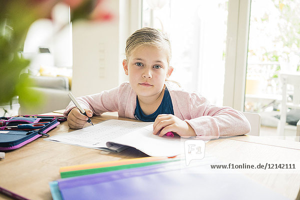 Porträt des Mädchens bei den Hausaufgaben am Tisch