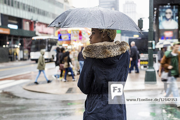 USA  New York City  junge Frau mit Regenschirm am Regentag