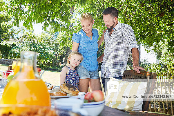 Smiling family with girl standing at garden table