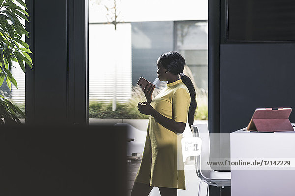 Businesswoman holding cell phone in office
