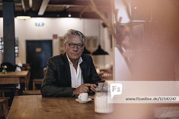 Geschäftsmann sitzend im Café  mit Smartphone
