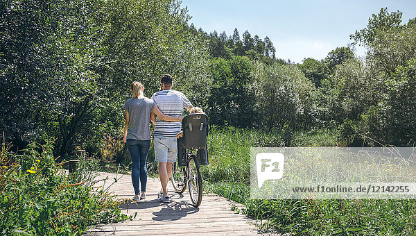 Family with bicycle walking on wooden walkway