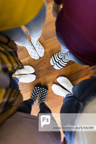 Close-up of feet of five women standing on wooden floor