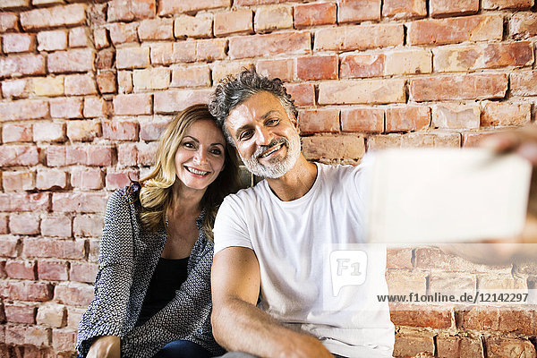 Geschäftsmann und Frau sitzen in ihrem neuen Büro und teilen sich das selfies