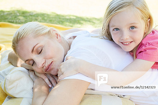 Mutter und Tochter entspannt auf einer Decke liegend