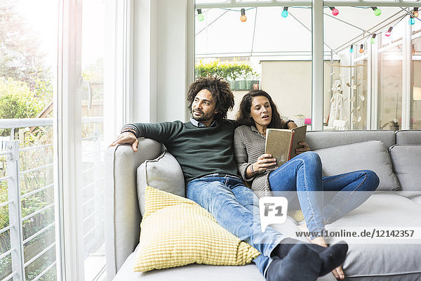 Couple sitting on couch reading book