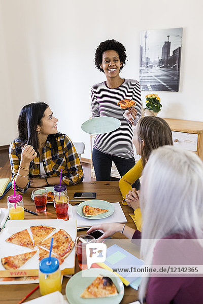 Gruppe junger Frauen zu Hause beim Lernen und Pizza essen