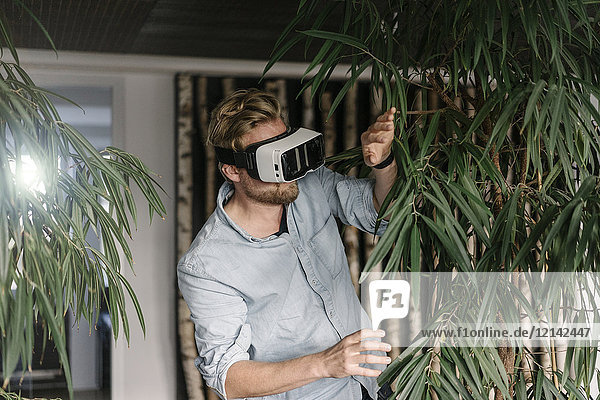 Man wearing VR glasses surrounded by plants