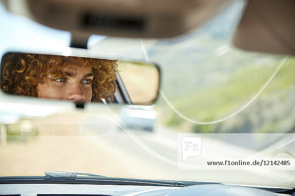 Junger Mann beim Autofahren  Rückspiegel  verspiegelt