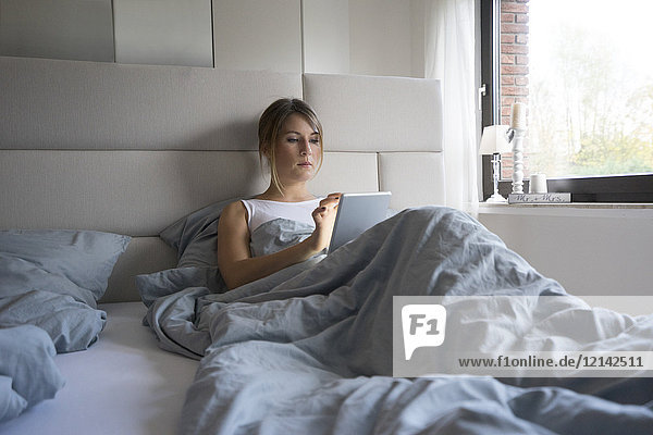 Frau im Bett zu Hause mit Tablette