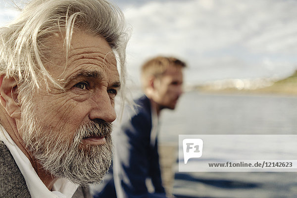 Porträt eines ernsthaften älteren Mannes an einem See mit Mann im Hintergrund