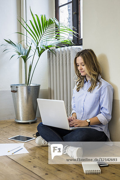Woman sitting on the floor at home using laptop